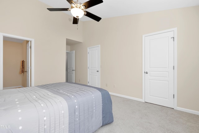 bedroom with connected bathroom, high vaulted ceiling, light colored carpet, and ceiling fan