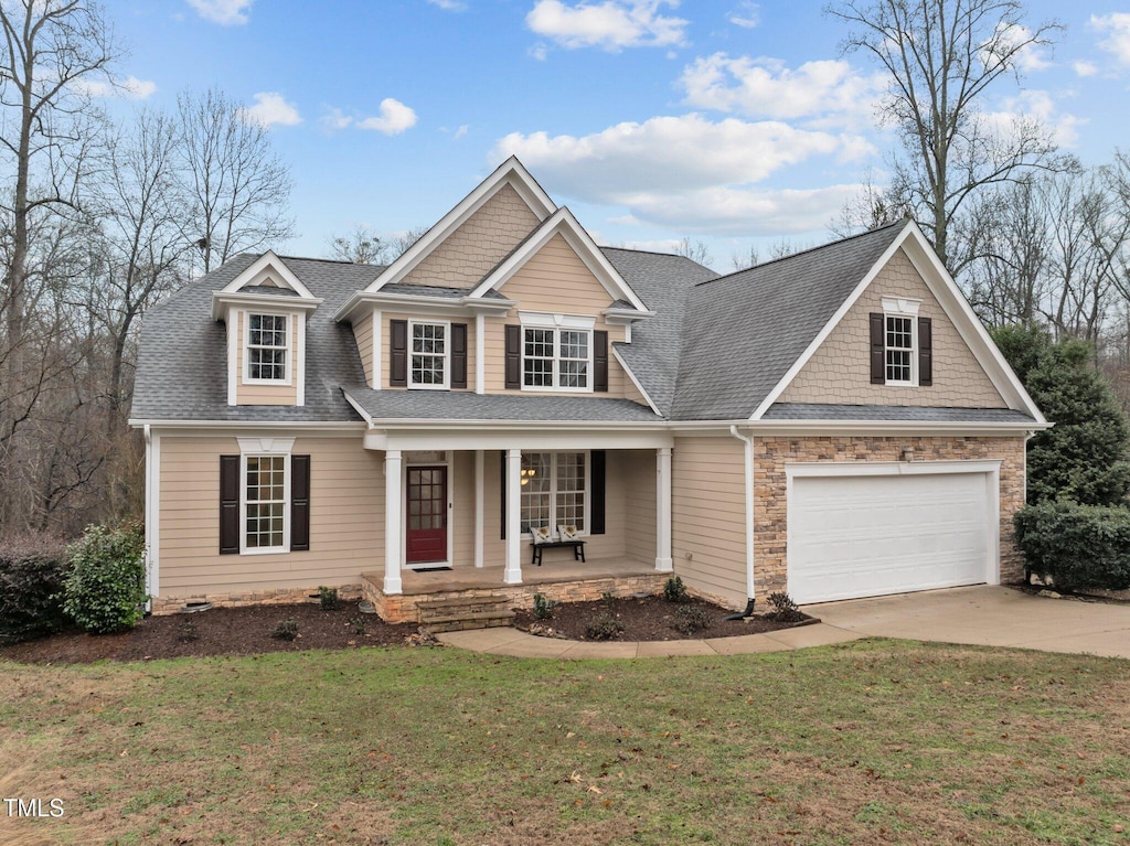 craftsman inspired home with a garage, a front yard, and covered porch