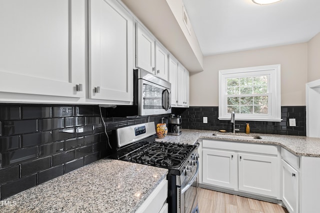 kitchen featuring sink, backsplash, white cabinets, light stone counters, and stainless steel appliances