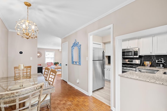 kitchen with decorative light fixtures, appliances with stainless steel finishes, white cabinets, light stone countertops, and light parquet floors