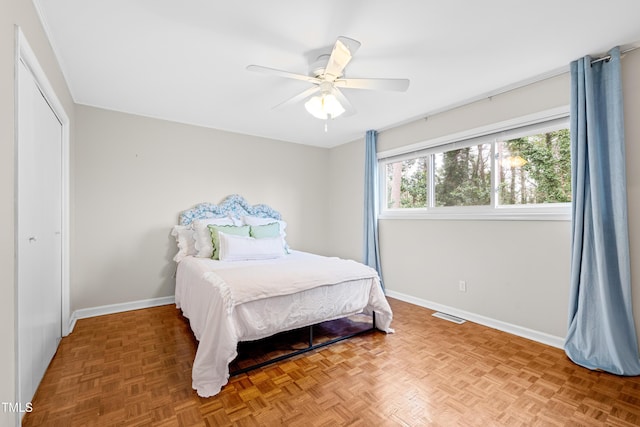 bedroom with parquet flooring, ceiling fan, and a closet