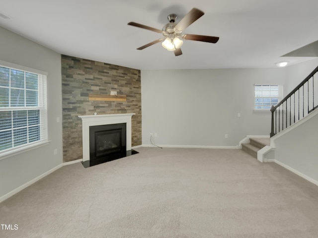 unfurnished living room featuring light colored carpet, a large fireplace, and ceiling fan