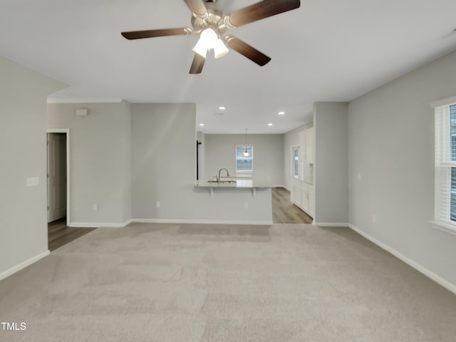 unfurnished living room with sink, light carpet, and a wealth of natural light