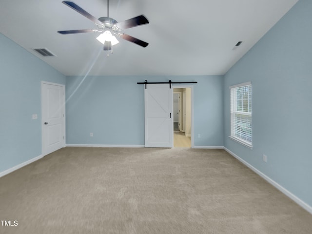 interior space featuring a barn door, light colored carpet, lofted ceiling, and ceiling fan