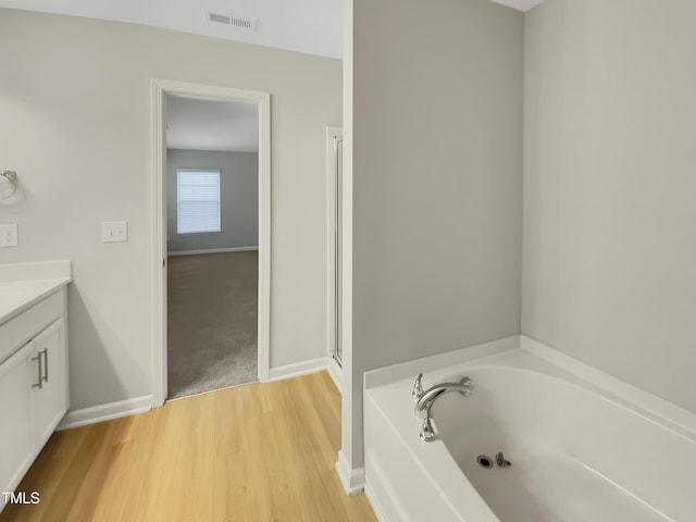 bathroom featuring hardwood / wood-style flooring, vanity, and a tub