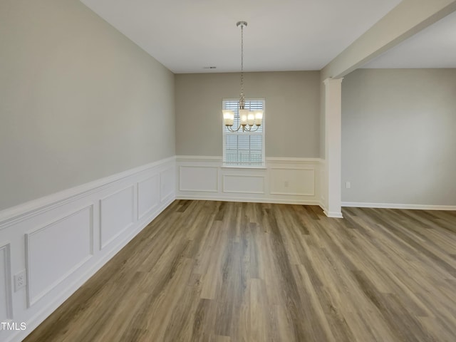 unfurnished dining area with a notable chandelier and light wood-type flooring