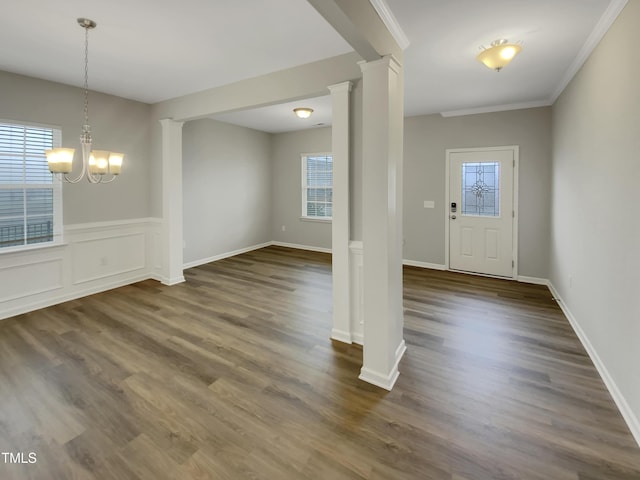 entrance foyer featuring an inviting chandelier, ornamental molding, dark hardwood / wood-style floors, and ornate columns