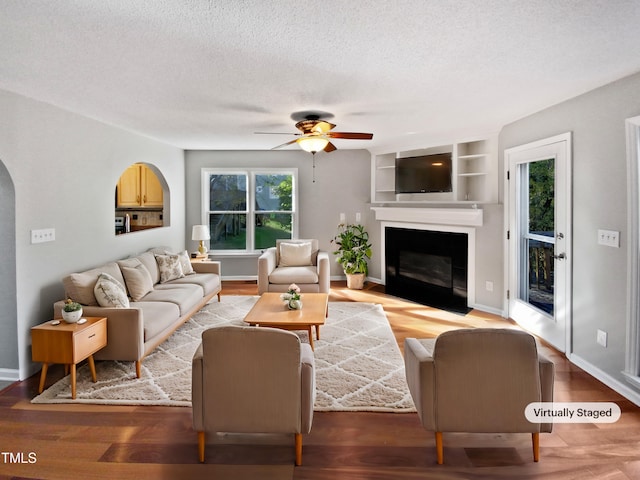 living room with ceiling fan, wood-type flooring, and a textured ceiling