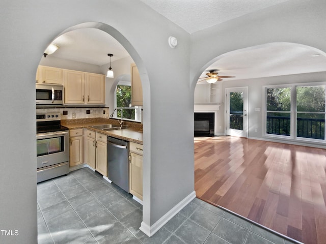 kitchen with sink, dark tile patterned flooring, pendant lighting, stainless steel appliances, and decorative backsplash