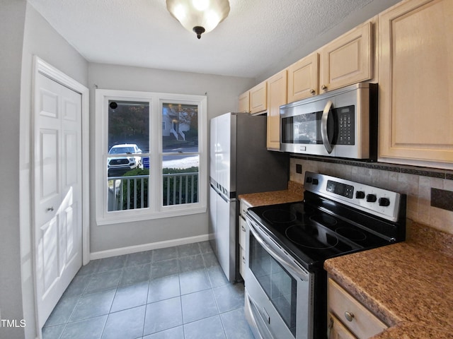 kitchen featuring tasteful backsplash, stainless steel appliances, light brown cabinetry, and tile patterned flooring