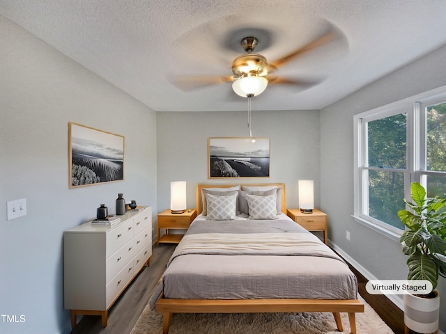 bedroom featuring ceiling fan, dark wood-type flooring, and a textured ceiling