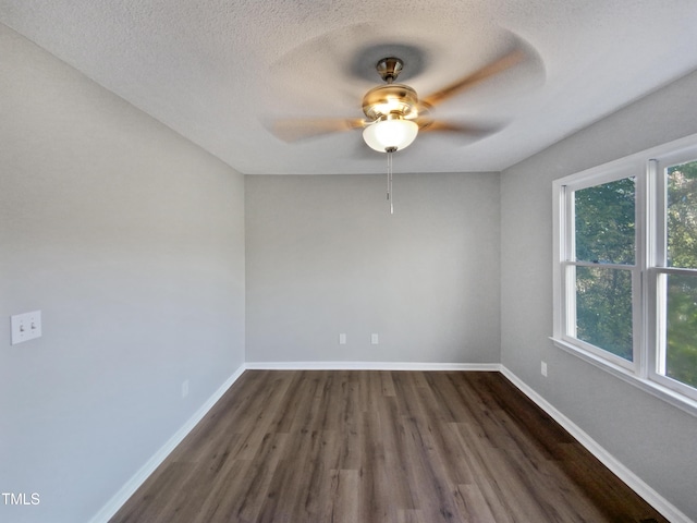 empty room with ceiling fan, dark wood-type flooring, plenty of natural light, and a textured ceiling