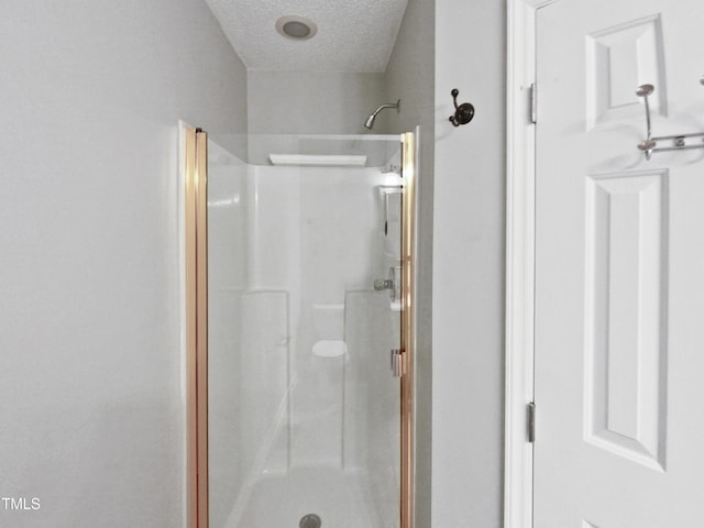 bathroom featuring a shower with door and a textured ceiling