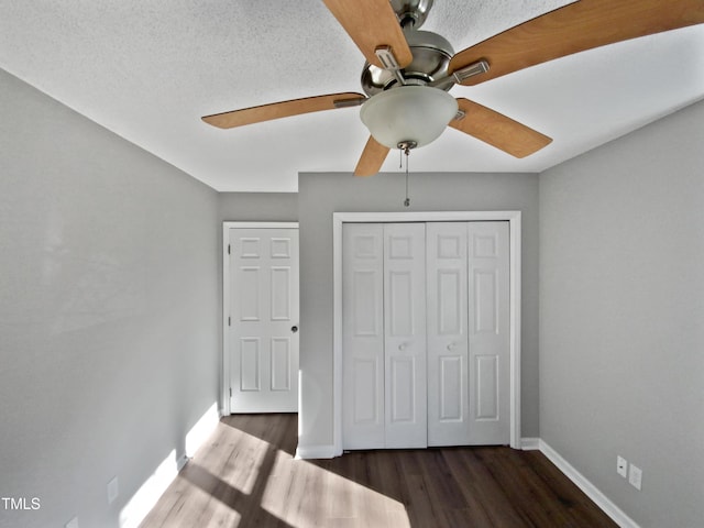 unfurnished bedroom with dark hardwood / wood-style flooring, a closet, and ceiling fan