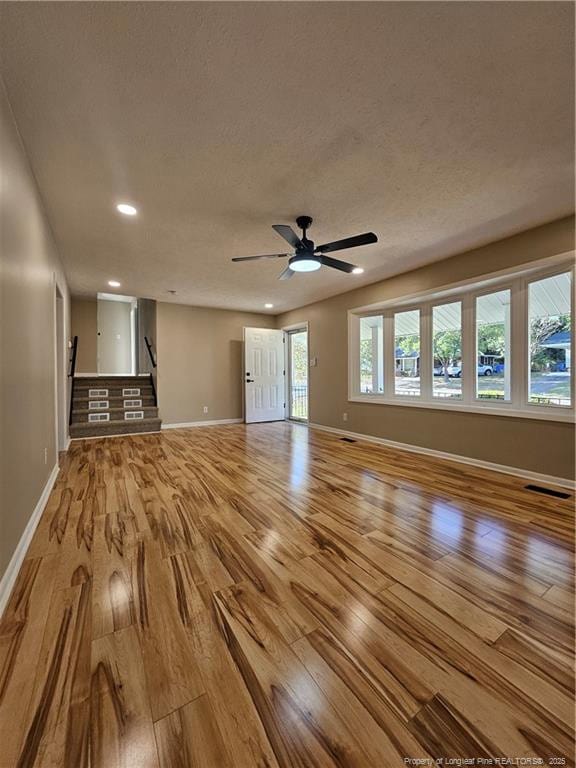 unfurnished living room featuring a textured ceiling, ceiling fan, and light wood-type flooring