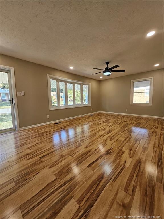 spare room featuring plenty of natural light, a textured ceiling, and light hardwood / wood-style floors