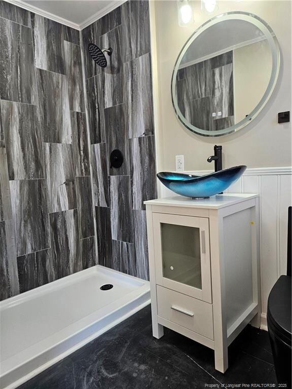 bathroom featuring crown molding, tiled shower, vanity, and toilet