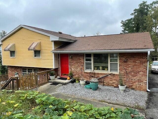 back of property with brick siding and a shingled roof