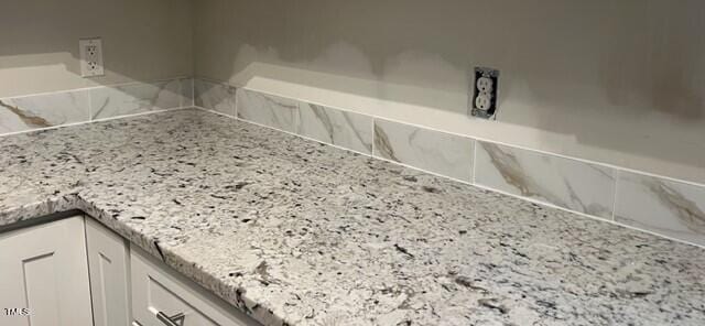 room details with light stone countertops and white cabinets