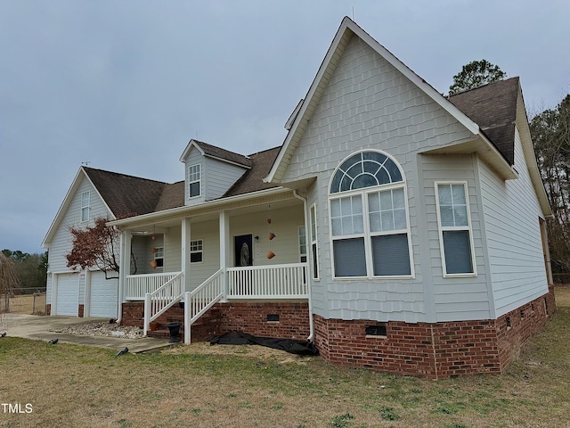 view of front of house featuring a garage, covered porch, and a front lawn