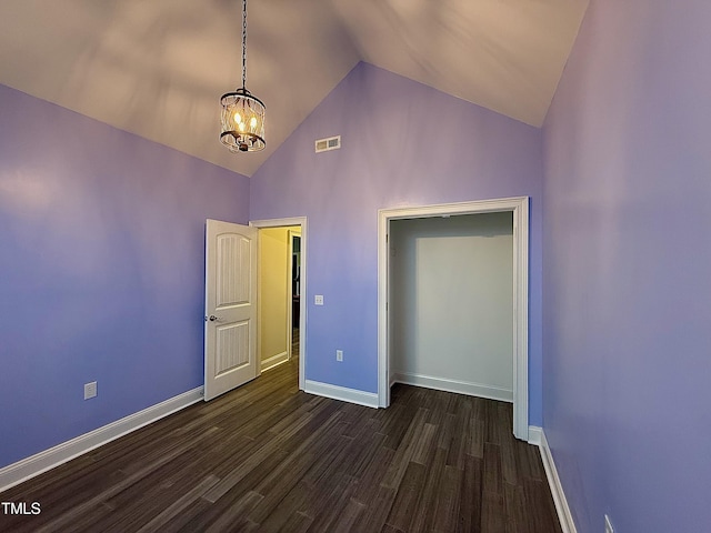 unfurnished bedroom featuring dark hardwood / wood-style flooring, high vaulted ceiling, and a chandelier