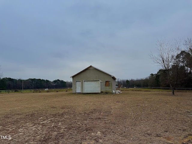 view of property exterior with a garage, an outdoor structure, and a rural view