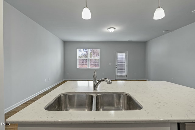 kitchen featuring decorative light fixtures, light stone countertops, and sink