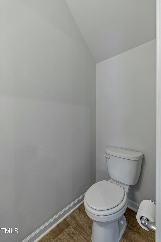 bathroom with hardwood / wood-style floors, vaulted ceiling, and toilet