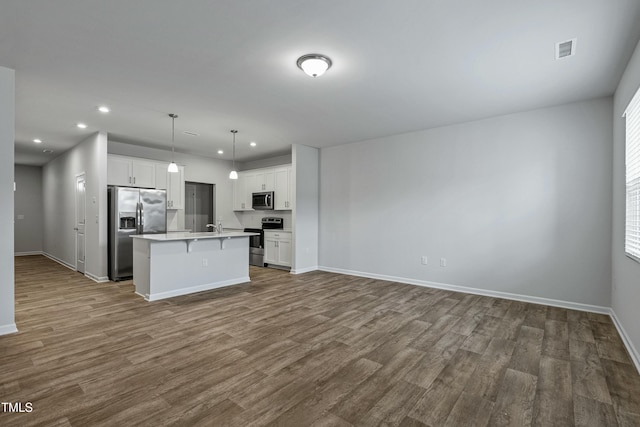 kitchen with pendant lighting, stainless steel appliances, white cabinets, and a kitchen island