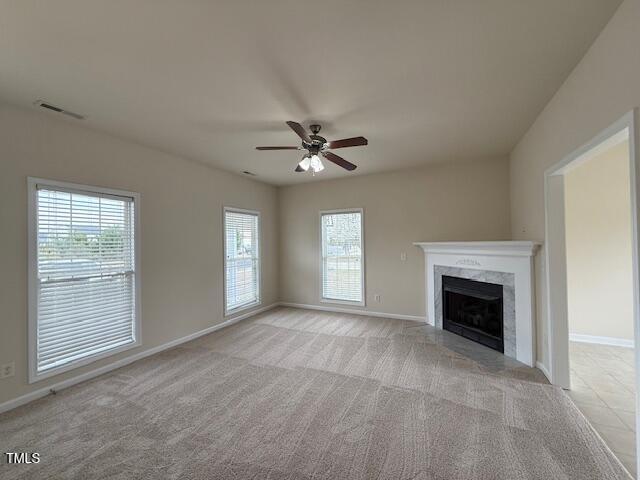 unfurnished living room with visible vents, baseboards, ceiling fan, and a fireplace