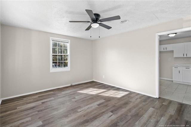 spare room with ceiling fan, a textured ceiling, and dark hardwood / wood-style flooring