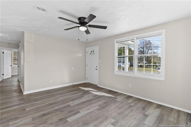 empty room featuring dark wood-type flooring, ceiling fan, and a textured ceiling