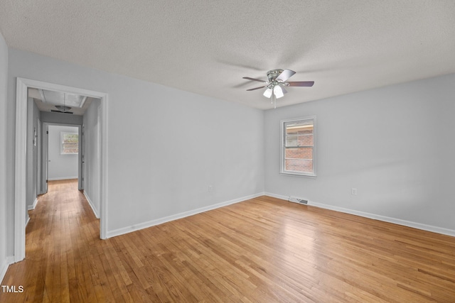 empty room with a textured ceiling, light hardwood / wood-style floors, and ceiling fan