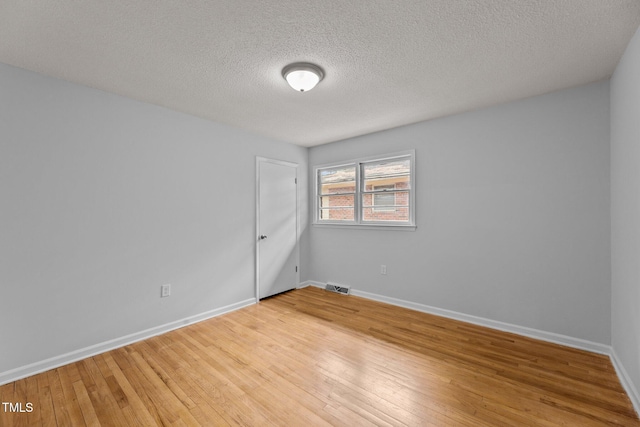 empty room featuring wood-type flooring and a textured ceiling