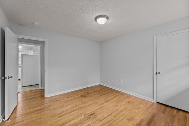 spare room with a textured ceiling and light hardwood / wood-style flooring