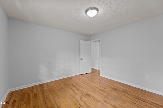 spare room featuring light hardwood / wood-style flooring and a textured ceiling