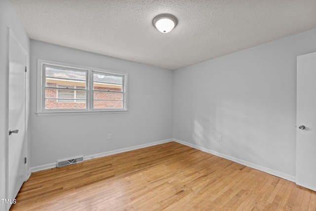 empty room featuring a textured ceiling and light wood-type flooring