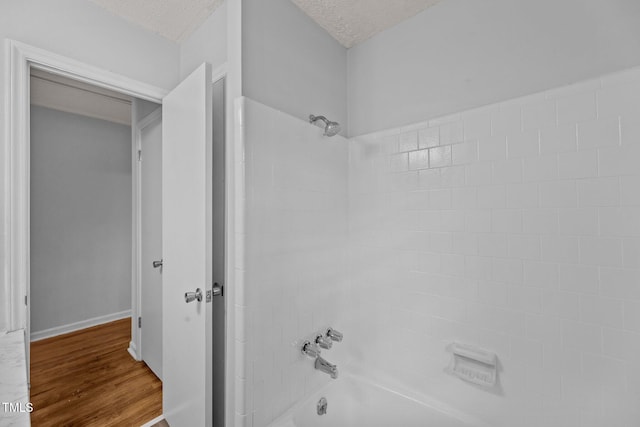 bathroom featuring hardwood / wood-style flooring, tiled shower / bath combo, and a textured ceiling