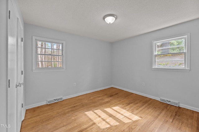 empty room featuring a textured ceiling and light wood-type flooring