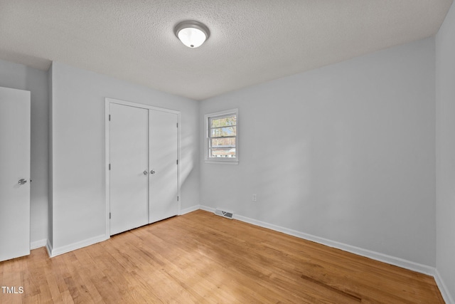 unfurnished bedroom featuring light hardwood / wood-style floors, a closet, and a textured ceiling