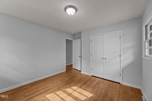 unfurnished bedroom with a textured ceiling, light hardwood / wood-style floors, and a closet