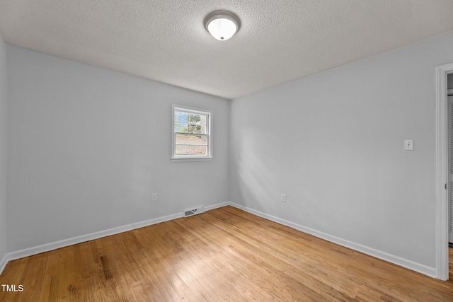 empty room with hardwood / wood-style flooring and a textured ceiling