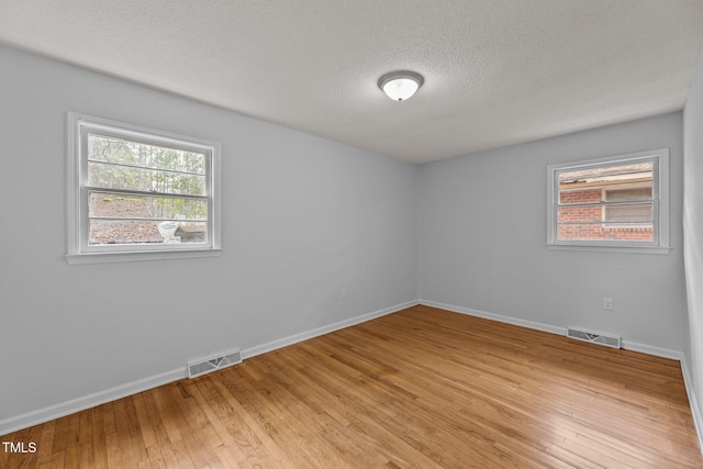 empty room with light hardwood / wood-style floors and a textured ceiling