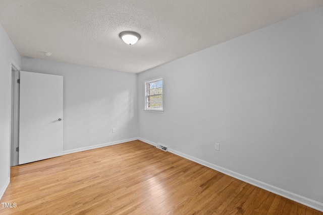 spare room with a textured ceiling and light wood-type flooring