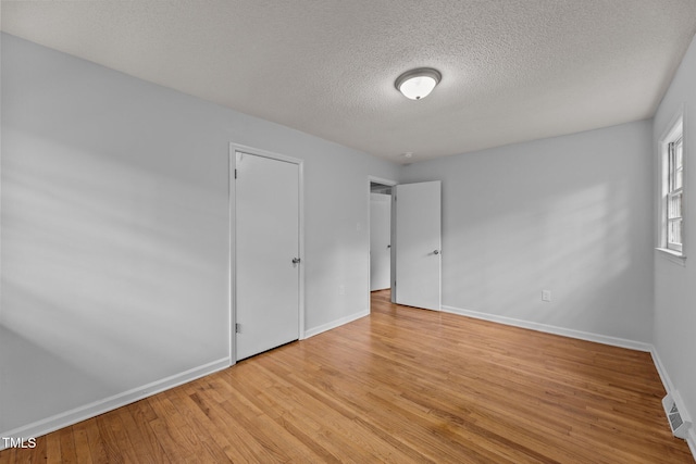 empty room with a textured ceiling and light wood-type flooring