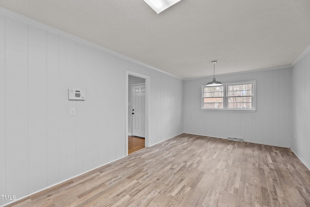 spare room with ornamental molding and light wood-type flooring