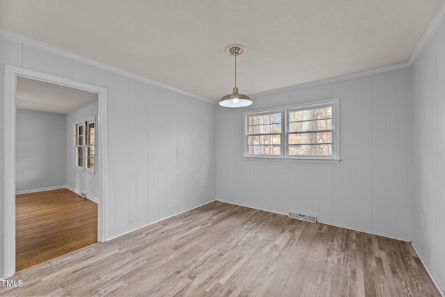 empty room with ornamental molding and light hardwood / wood-style floors