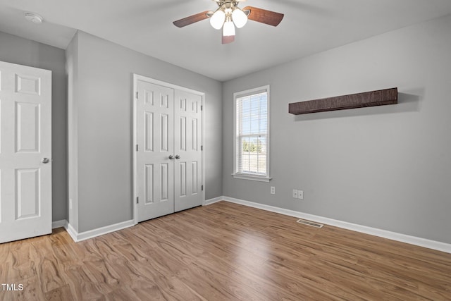 unfurnished bedroom featuring ceiling fan, light hardwood / wood-style floors, and a closet