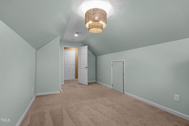 bonus room featuring an inviting chandelier, vaulted ceiling, and light colored carpet