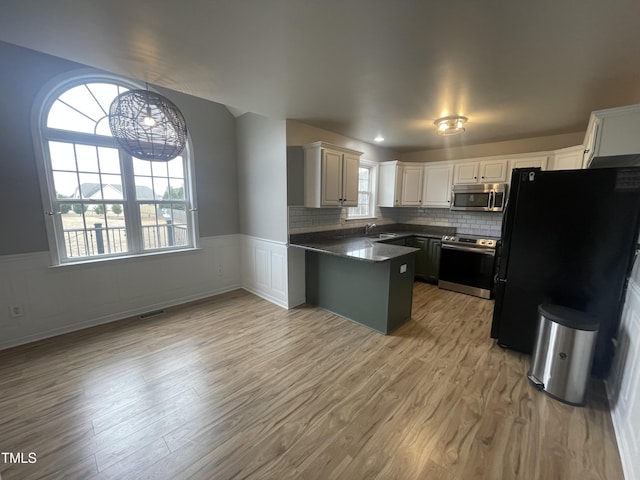 kitchen featuring sink, white cabinetry, appliances with stainless steel finishes, light hardwood / wood-style floors, and backsplash